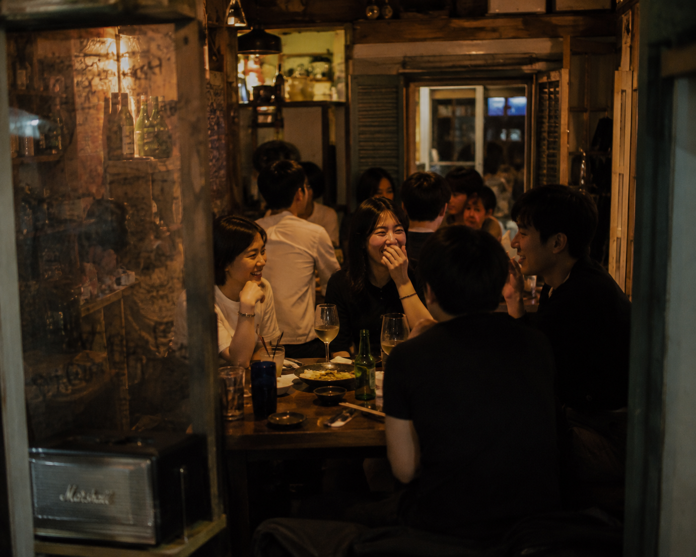 Friends laughing and drinking together at a late-night Korean bar in Seoul