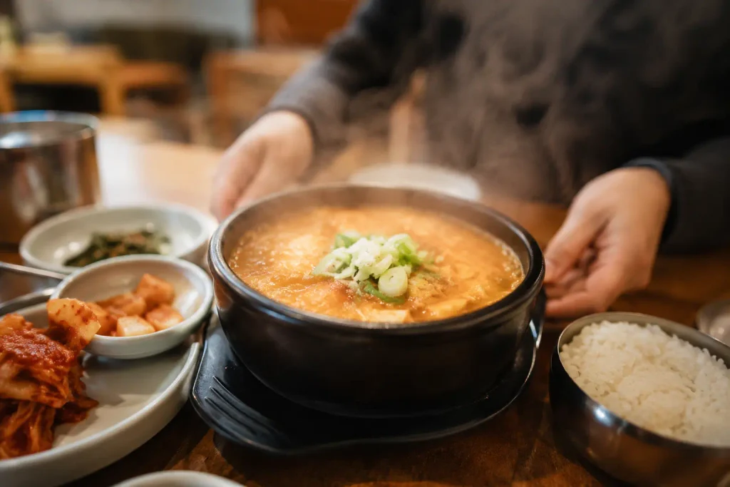 Hot Korean soup in a stone bowl with rice and side dishes