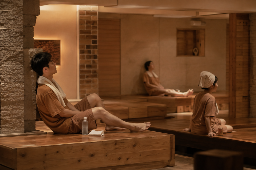 Young Korean adults relaxing after exercise in a contemporary jjimjilbang sauna lounge